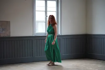 Andrea Kirste in grünem Kleid in einem leeren Raum