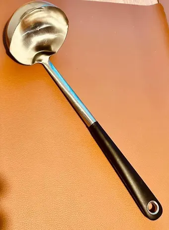 Eine goldene Schöpfkelle auf orangefarbenem Grund